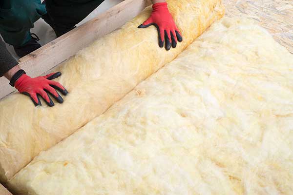 Installing rolls of new high efficiency loft insulation